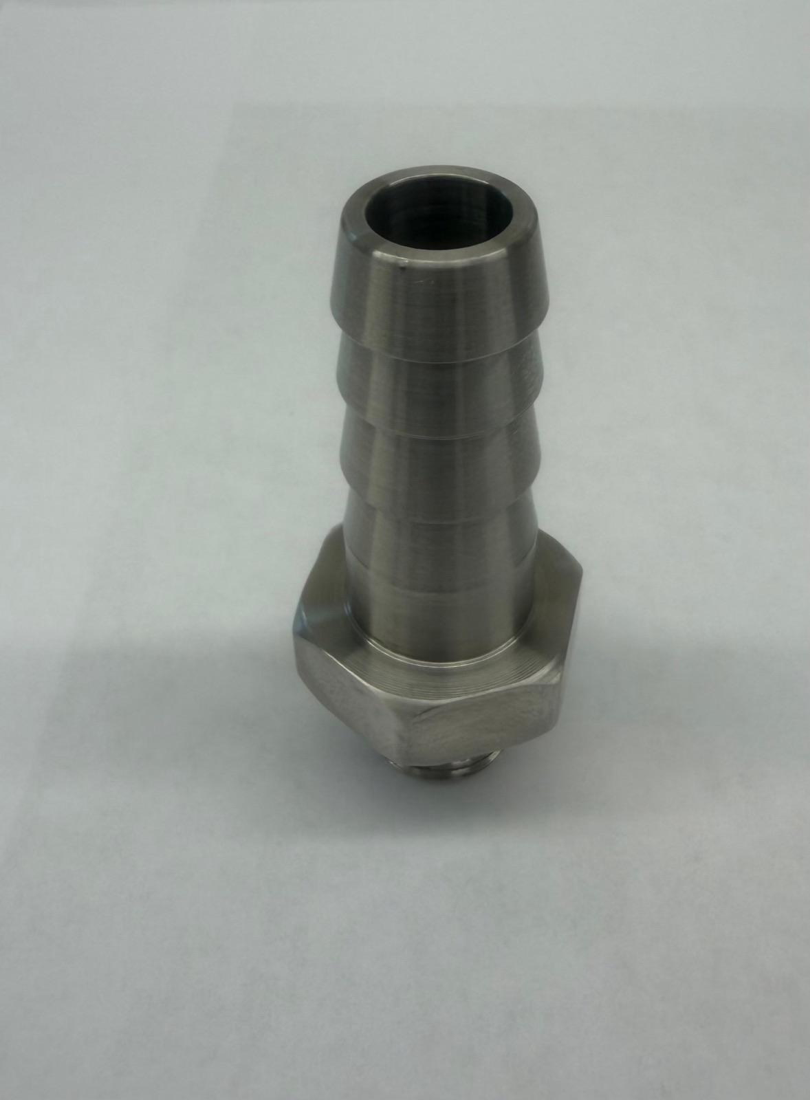 A turned hose barb fitting seen from the bore end, with a milled hex