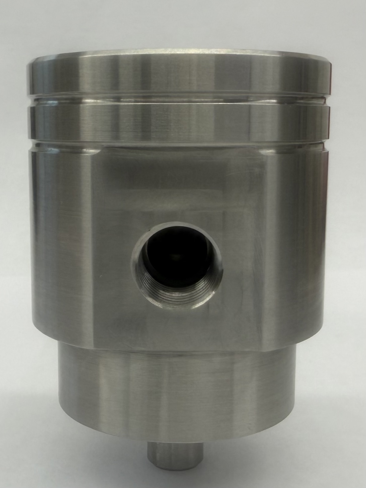 Front view of a machined housing showing a threaded port in a milled flat