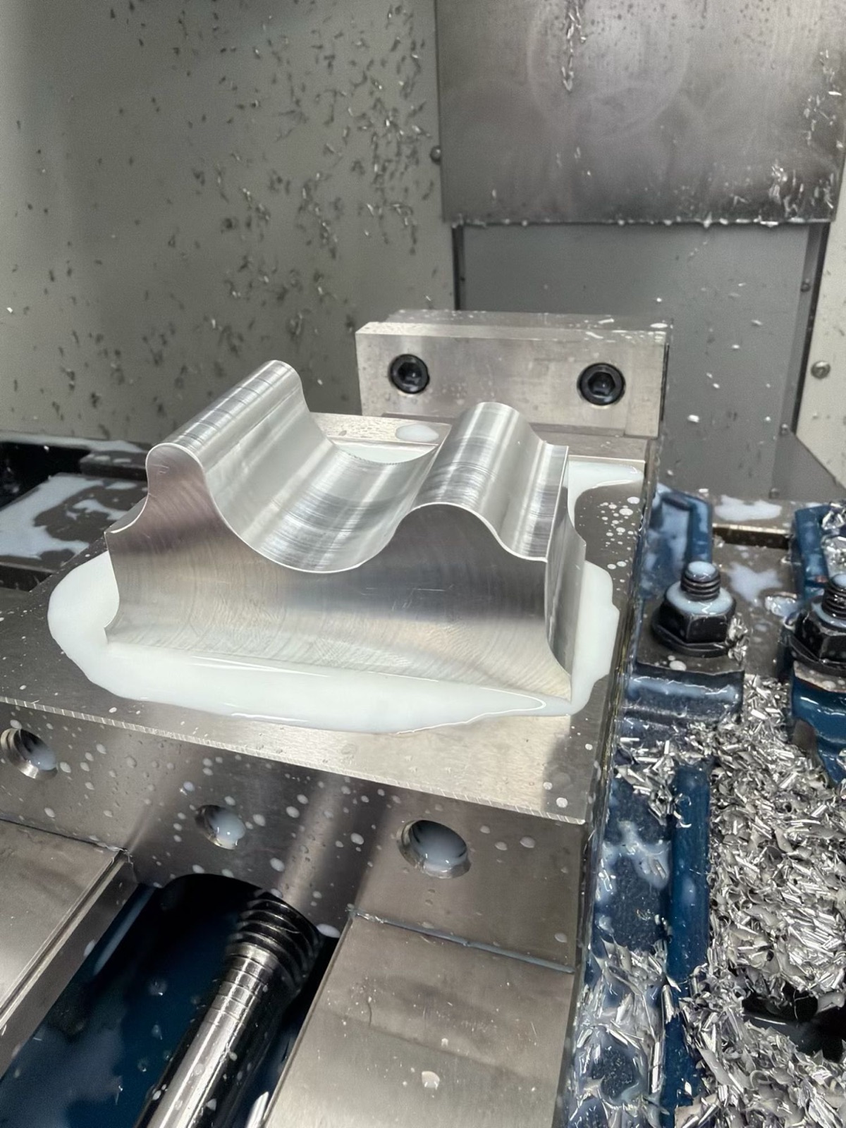 A contoured block being milled, still clamped in the vise