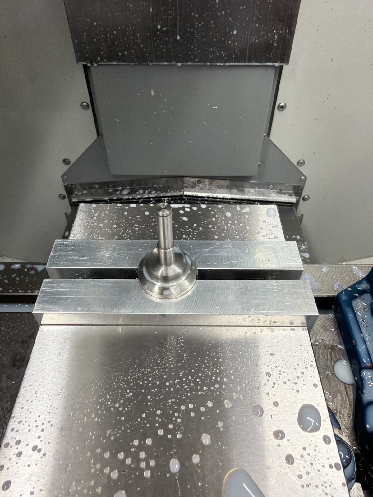 A small turned stepped pin standing on a mill vise after a milling operation